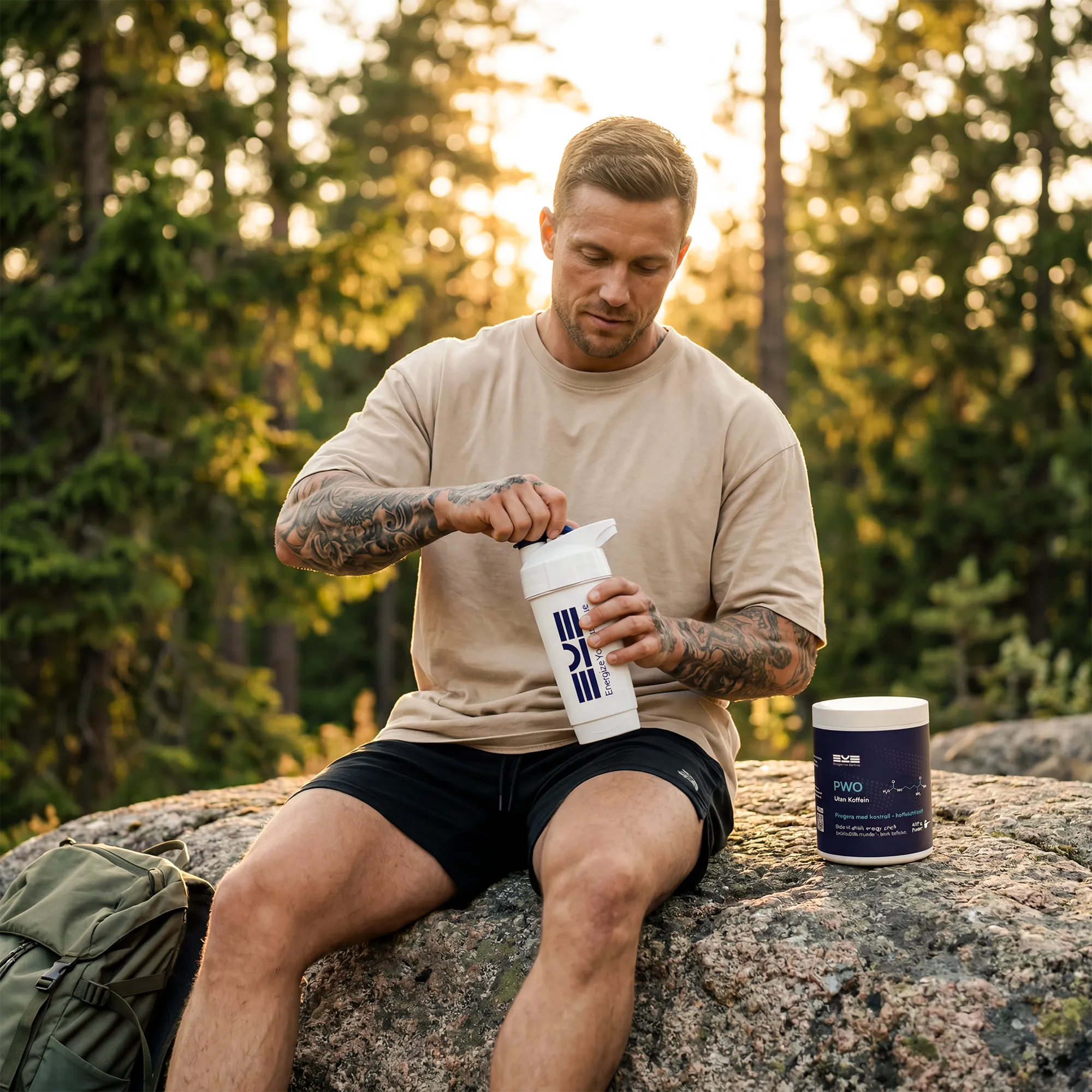 Man blandar PWO utan koffein från Energize Your Essence i shaker utomhus på klippa i skogsmiljö, med ryggsäck och burk bredvid i varmt kvällsljus