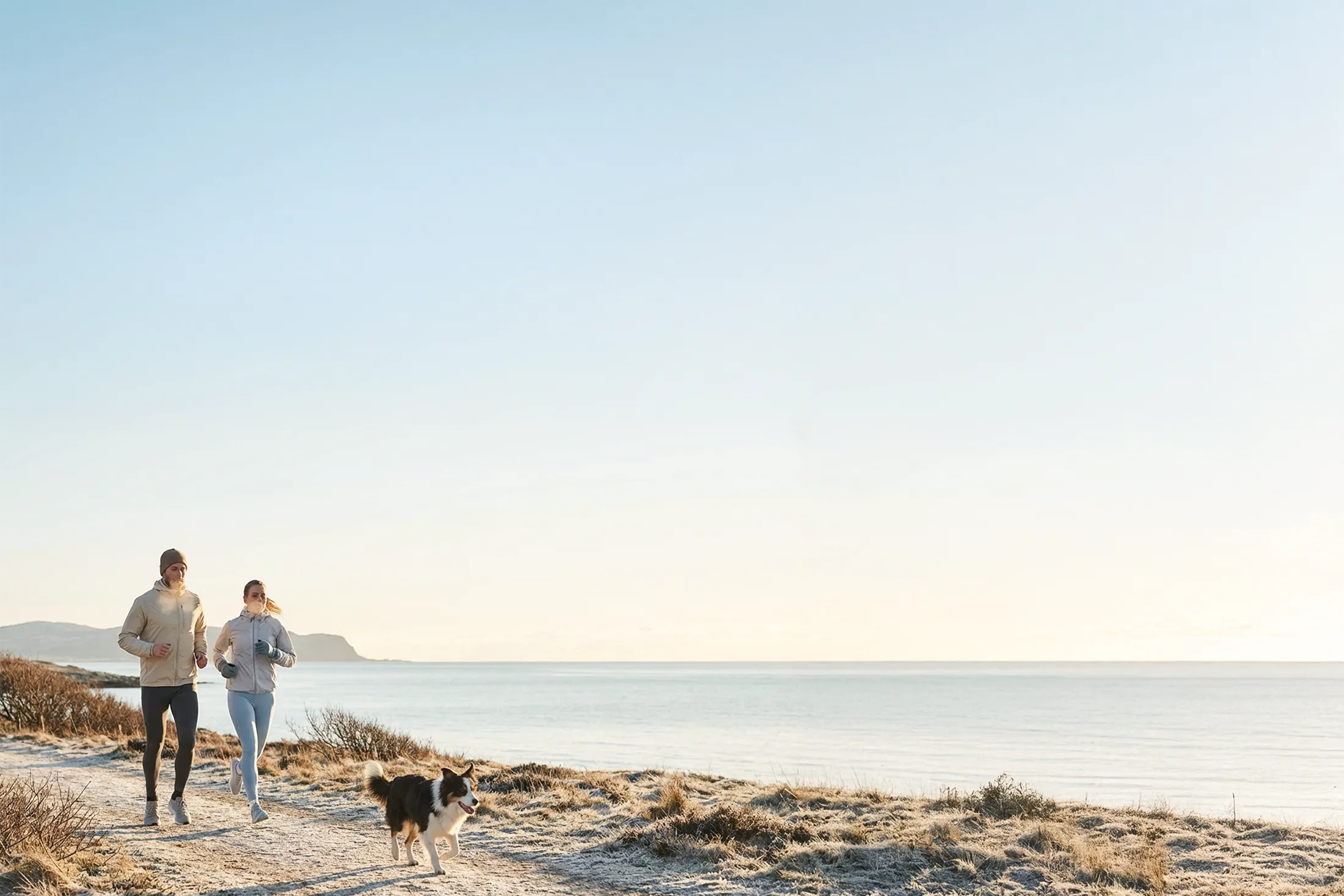 Par joggar längs kust i morgonljus – symbol för balans, energi och en aktiv livsstil i harmoni med naturen