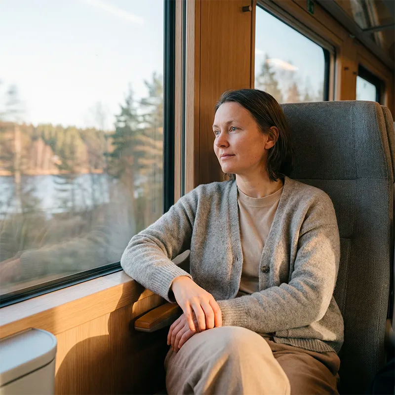 Person som sitter vid tågfönster och blickar ut över landskapet – reflektion, inre balans och livets resa